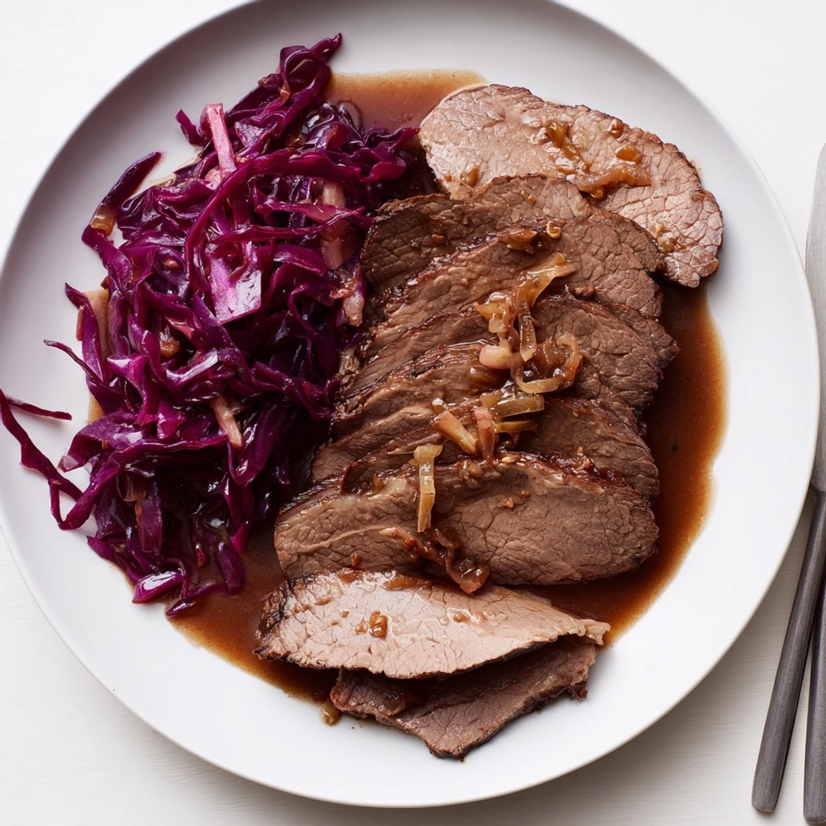 Zartes Sauerbraten mit rotem Kohl, geschmort und mit reichhaltiger Soße serviert.  