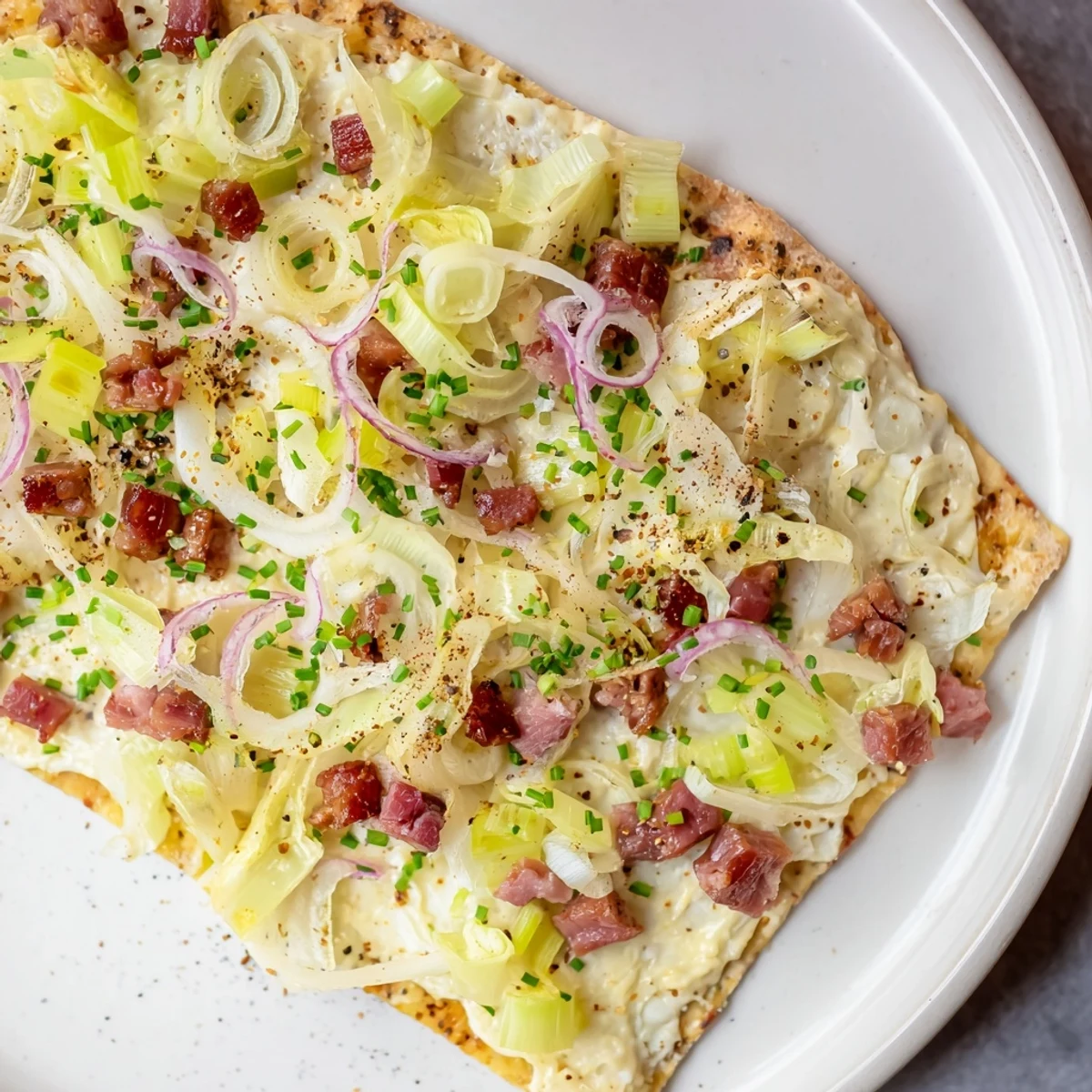 Crispy Sheet-Pan Flammkuchen Style Flatbread, featuring bacon, leeks, and bubbly crème fraîche.