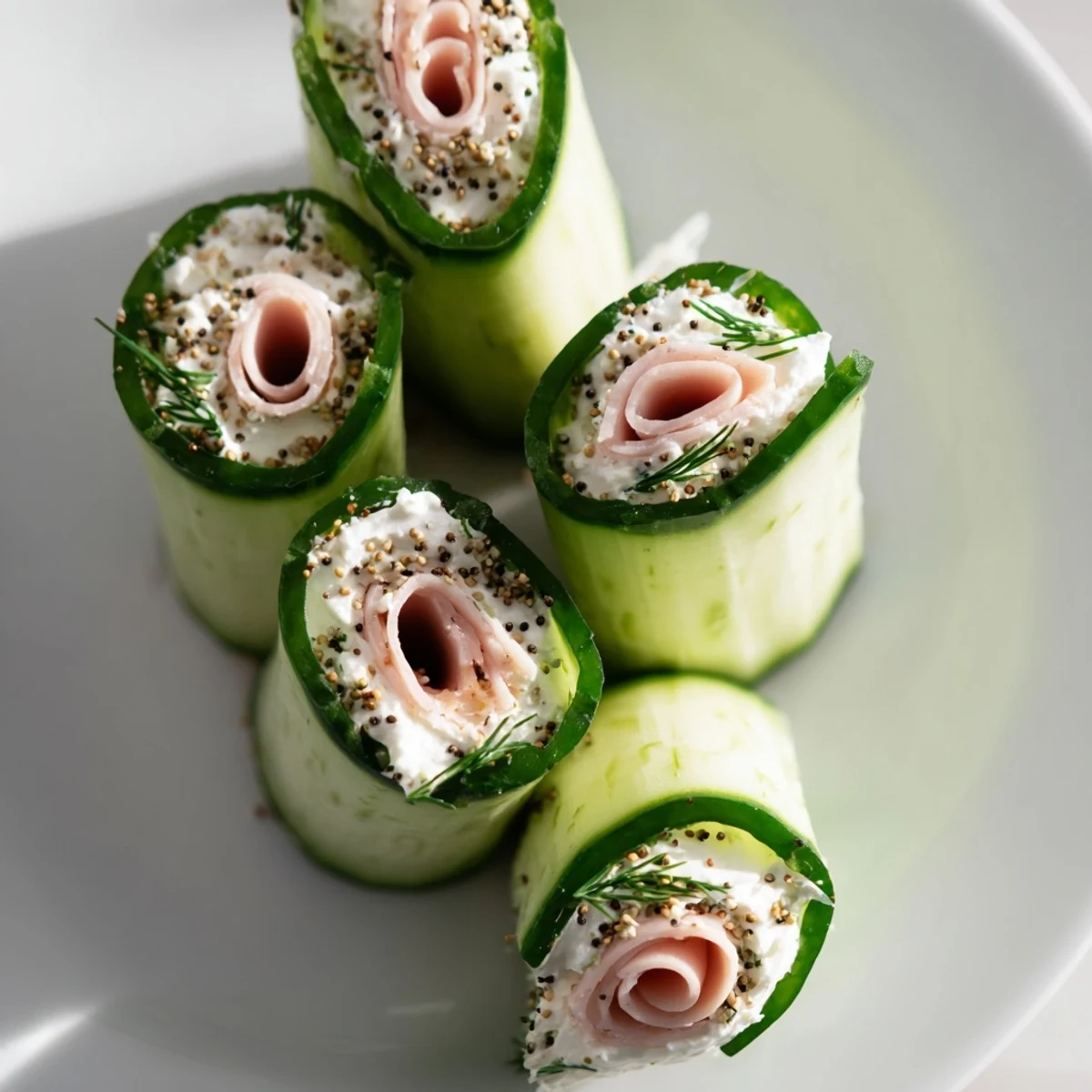Close-up of Cucumber Roll-Ups: Deli meats and cream cheese rolled inside crisp cucumber slices.
