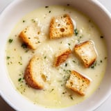 Warm bowl of Creamy Garlic Bread Soup, garnished with parsley, offering a delightful, comforting aroma.
