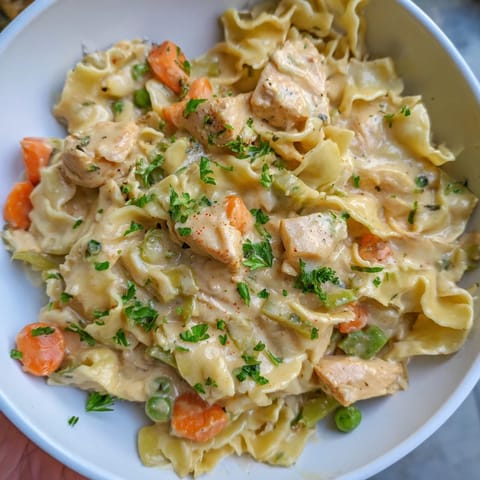 Steaming Creamy Chicken and Egg Noodles, topped with fresh parsley for serving.