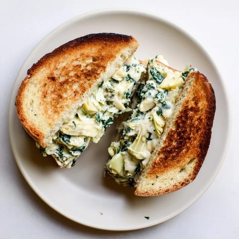 Frisches Artichoke Spinach Grilled Cheese sandwich auf goldenem Sauerteigbrot geschmolzen.