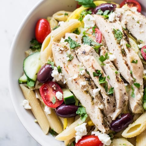 Greek Chicken Pasta Bowl with marinated chicken, cherry tomatoes, olives, and creamy feta cheese.