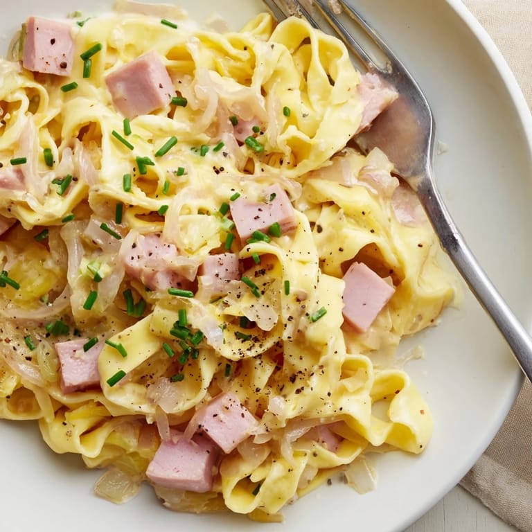 Herzhafte deutsche Schinken-Nudeln, perfekt garniert mit gehacktem Schnittlauch.  